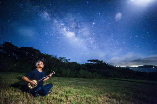 Sanshin (Okinawan lute) player performing under the Milky Way at Nagareboshi Hill, Hirakubo Peninsula, Ishigaki Island