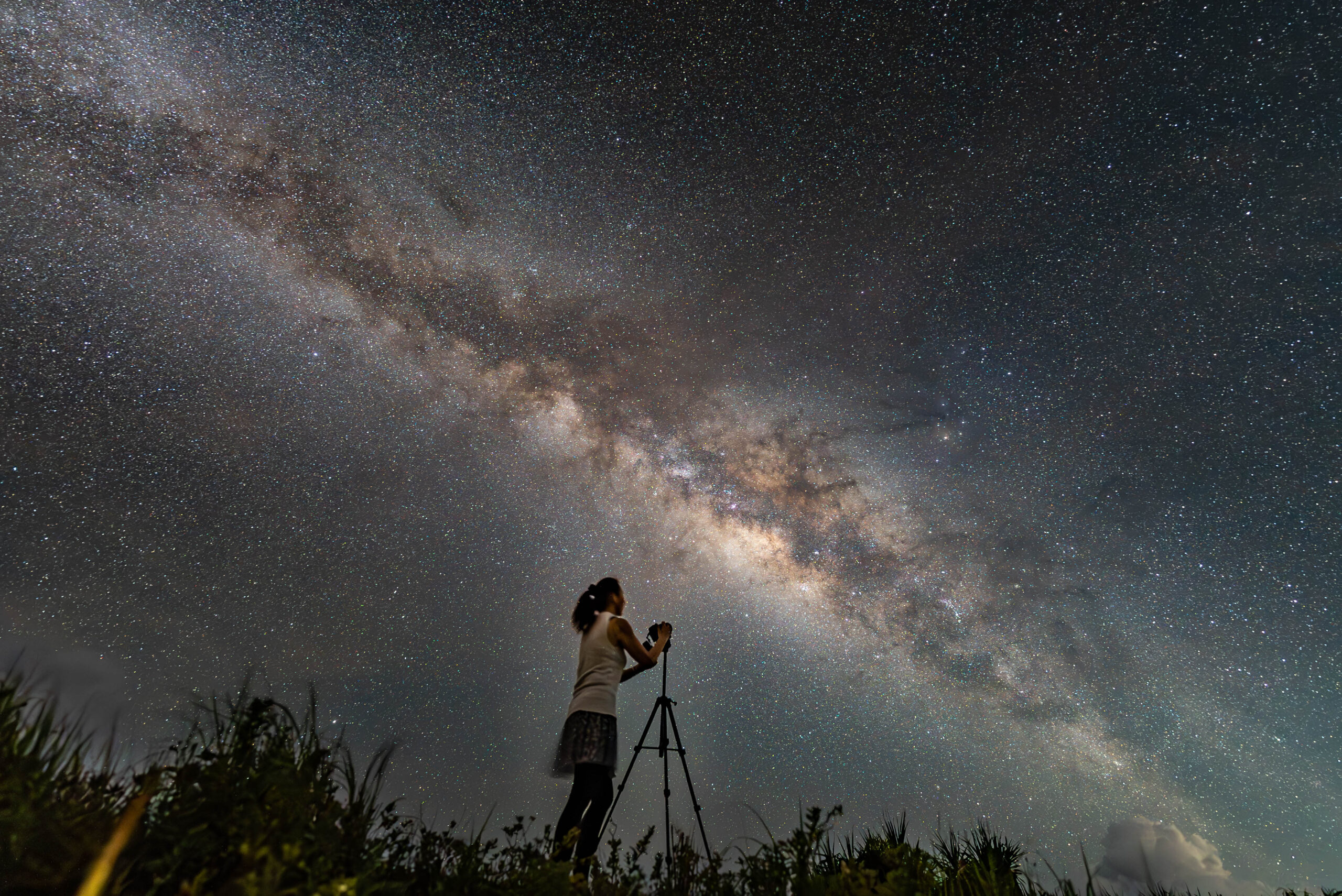 Person photographing the Milky Way with camera on tripod at Nagareboshi no Oka, Ishigaki Island