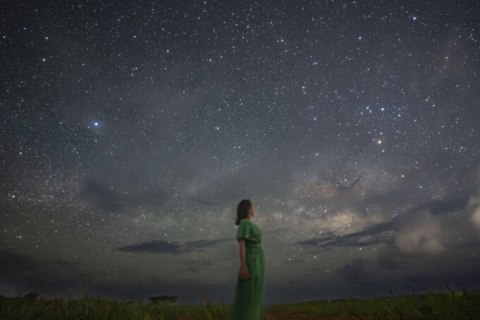 Woman in green dress looking up at the Milky Way at Nagareboshi no Oka, Ishigaki Island (cropped)
