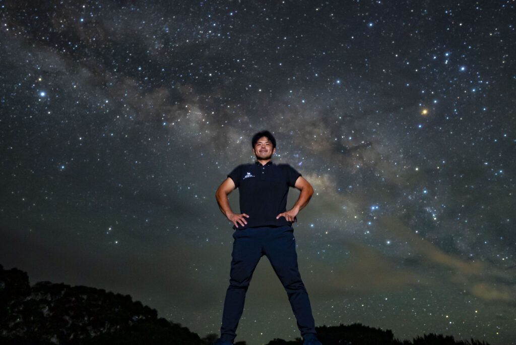 Tour guide posing under the Milky Way at Nagareboshi no Oka stargazing tour, Ishigaki Island