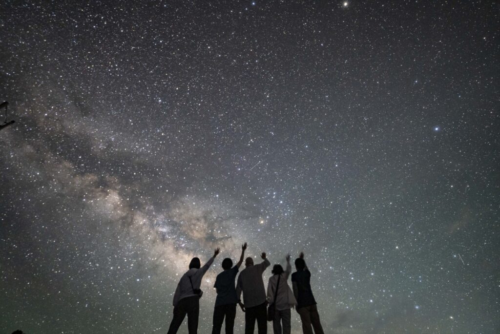 石垣島の天の川の下でシルエットポーズをとるグループ