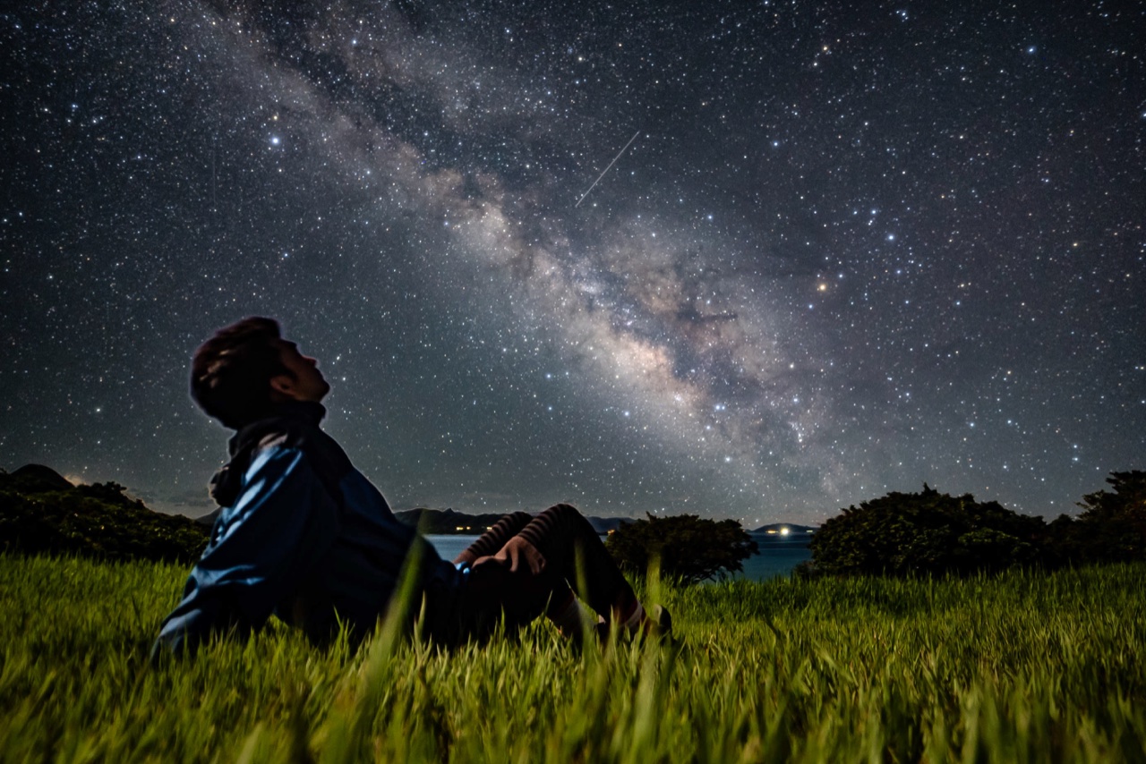 Man sitting milky way grassfield at Nagareboshi no Oka stargazing spot, Ishigaki Island