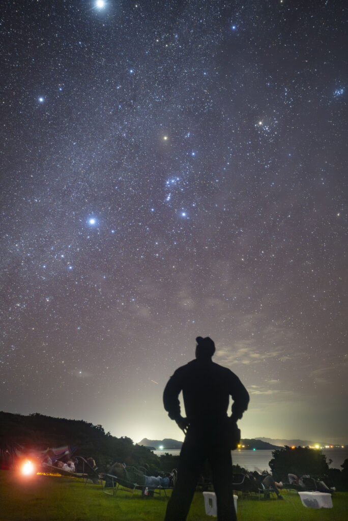 Stargazer silhouette looking up at winter night sky with Canopus visible at Nagareboshi Hill, Ishigaki Island